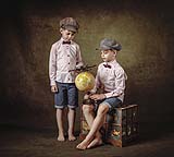 Two young boys in an old style fine art portrait looking at a globe of the world, Limerick. Ireland.  